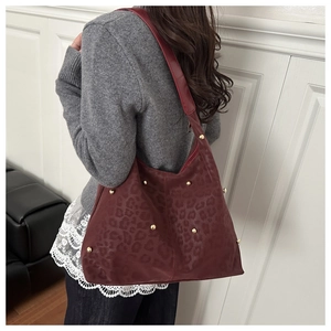 Dettaglio della borsa tote in pelle scamosciata bordeaux con stampa leopardata e borchie