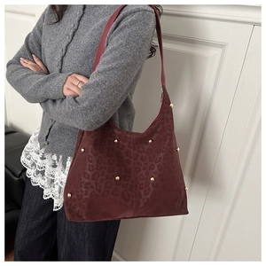 Detail of dark red leopard print hobo bag with gold rivet studs worn on shoulder