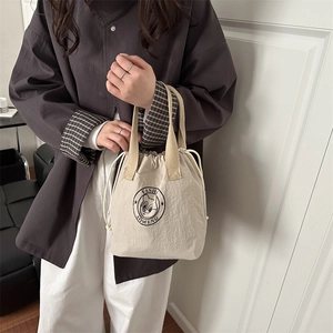 Fashionable beige drawstring bucket bag with cartoon cat logo for commuting and daily use