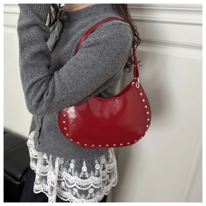 Détail du sac croissant rouge avec rivets dorés et finition en cuir verni brillant