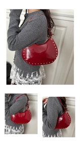 Vue détaillée du sac croissant rouge verni avec des rivets dorés sur le bord inférieur