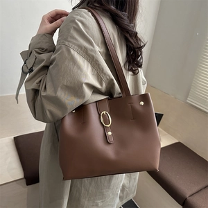 Japanese style large brown tote bag with gold buckle shown on a model in a minimalist room