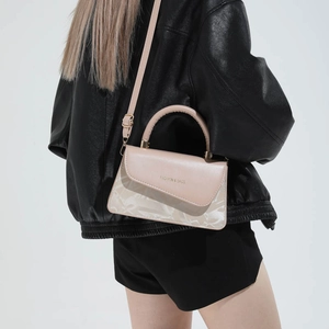 Sac carré minimaliste en cuir beige avec poignée et bandoulière porté par un mannequin