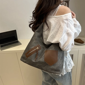 Large charcoal canvas tote bag with brown leather trim and metal zipper for daily commute