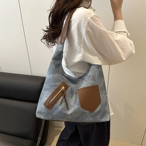 Retro washed denim tote bag with brown leather handles worn by a model in a minimal room