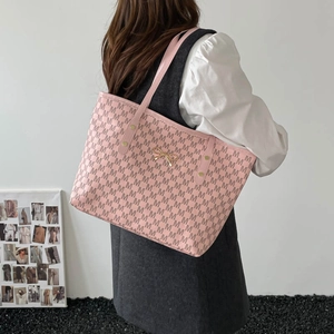 Pink tote bag with M-letter pattern and gold bow charm shown in a lifestyle setting