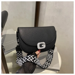 Close-up of black lychee leather saddle bag with rhinestone G buckle and woven strap