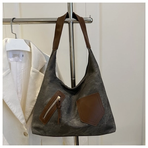 Detail of gray canvas tote bag featuring brown leather trim and diagonal zipper pocket