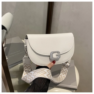 Detail of white lychee leather saddle bag featuring a sparkling silver G-buckle and woven strap