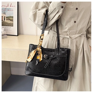 Close-up of black crocodile embossed tote bag with floral silk scarf decoration
