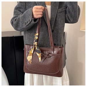 Detail of dark brown faux crocodile leather tote bag with silk scarf and contrast stitching