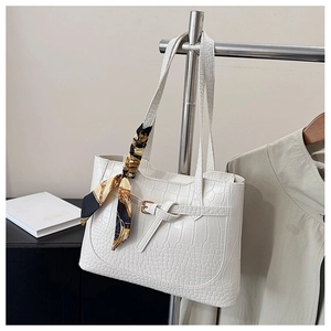 Detail of white crocodile texture tote bag with silk scarf and decorative buckle detail