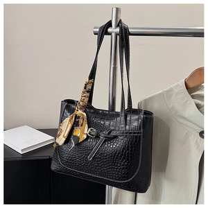 Detail of black croc-effect tote bag with contrast stitching and floral handle scarf