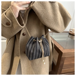 Detail of woven bucket bag with chevron pattern, gold chain and pearl accents