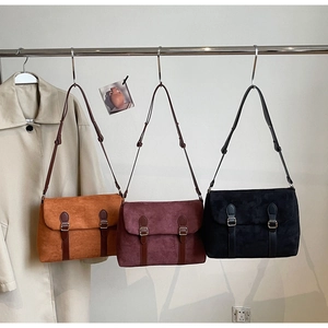 Detailed view of matte suede messenger bags in caramel, burgundy and black colors