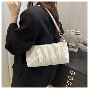 Detail of white pleated underarm bag with woven shoulder strap and gold metal hardware