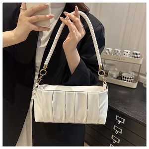 Detail of white pleated underarm bag featuring a woven strap and gold metal ring hardware