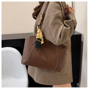 Detail of dark brown tote bag featuring contrast white stitching and floral silk scarf