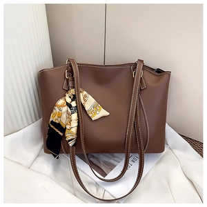 Detail of dark brown tote bag featuring contrast white stitching and decorative silk scarf