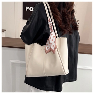 Detail of off-white tote bag with pink polka dot scarf on a model's shoulder
