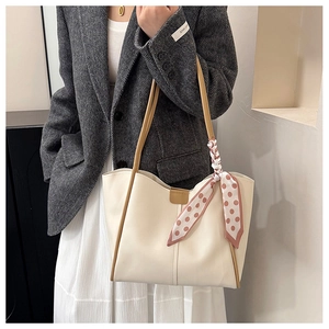 Close-up of cream tote bag with brown straps and pink polka dot silk scarf detail