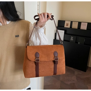 Close-up of brown suede messenger bag with vintage leather straps and metal buckles