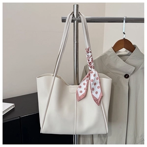 Detail of cream leather tote bag with a pink polka dot scarf on the handle