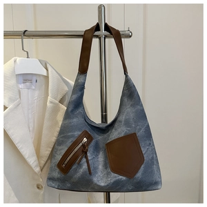 Detail of vintage canvas tote with brown leather accents hanging on a clothing rack