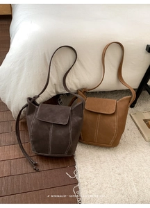 Detail view of large retro bucket bags showing contrast white stitching and matte leather