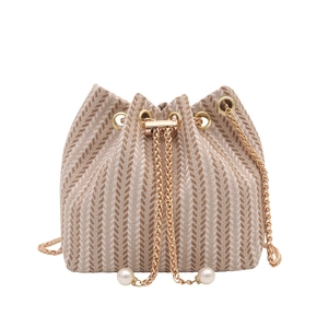 Woven bucket bag with golden chain strap and pearl accents on white background