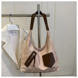 Detail of a large tote bag featuring beige fabric and brown leather patchwork design