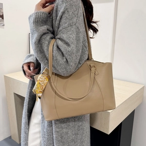 Elegant khaki leather tote bag with silk scarf accent for women on white background