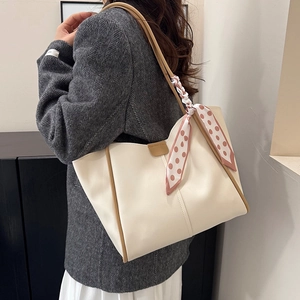 Chic beige tote bag with brown leather trim and a stylish polka dot scarf accessory