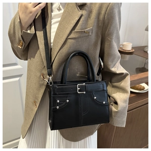 Detail of a black leather handbag with silver studs and buckle on office blazer