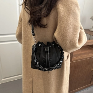 Matte black drawstring bucket bag with thick chain handle and long adjustable shoulder strap