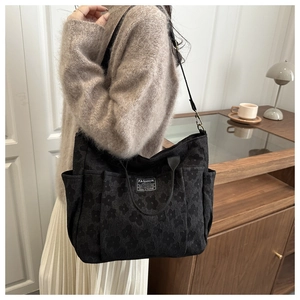 Detail of black embossed canvas tote bag with adjustable strap and side pocket