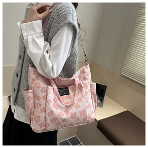 Detail of pink floral canvas tote bag featuring multiple pockets and durable shoulder strap