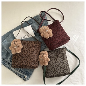 Three suede leopard print crossbody bags in brown, burgundy, and green with bear charms