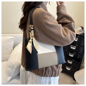 Detail of color-block tote bag with decorative beige silk scarf on handle for daily use