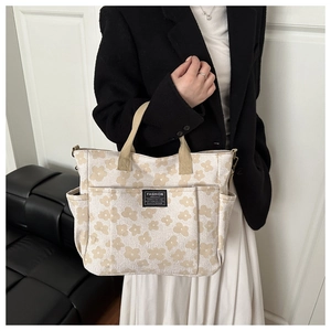 Detailed close-up of cream canvas tote bag with daisy floral prints and side pockets