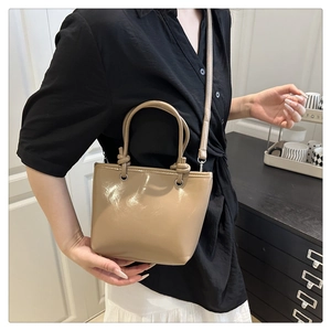 Détail du sac seau en cuir verni beige avec poignée polie et bandoulière réglable pratique
