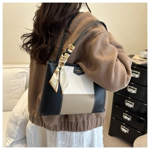 Close-up of tricolor leather tote bag with elegant silk scarf wrap on the handle