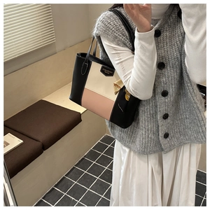 Close-up of tricolor patchwork tote bag with fashion label and silk scarf accessory