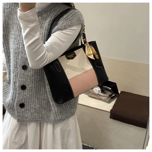 Close-up of color-block tote bag with leather texture and decorative silk scarf handle