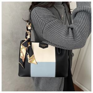 Detail of tricolor leather tote bag with printed silk scarf handle and logo plaque