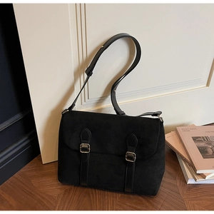 Detail of retro black suede crossbody bag featuring gold metal buckles and adjustable strap