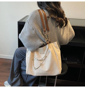 Détail du sac fourre-tout blanc cassé avec chaîne en perles et breloque florale élégante