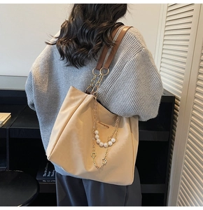 Detail of elegant shoulder strap with white pearls and gold metal chain on tote bag