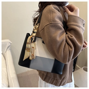 Detail of color-block tote bag with leather texture and decorative printed scarf