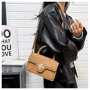 Detailed close-up of brown textured small square bag with golden camellia flower twist lock